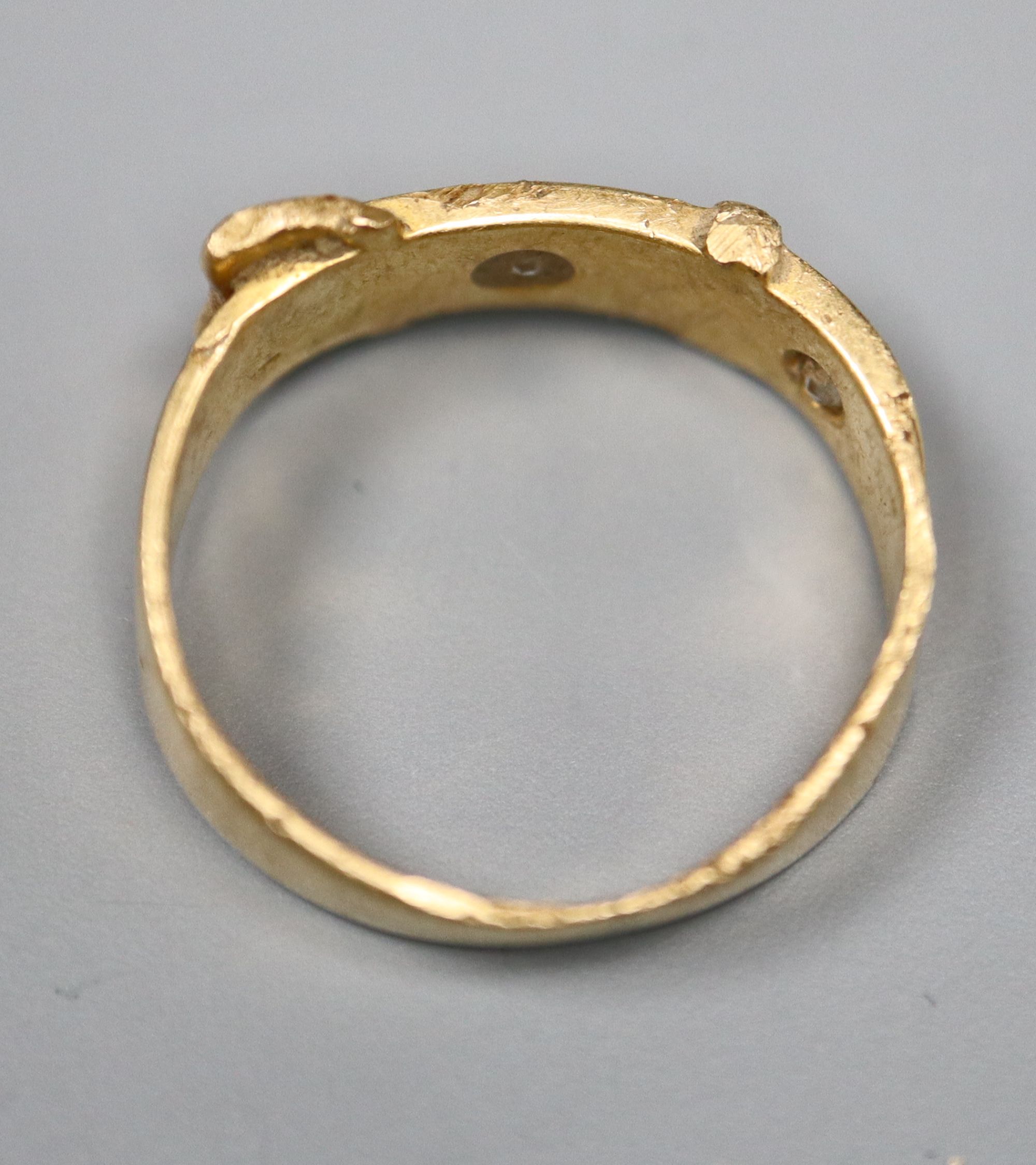 An early 20th century 18ct? gold and two stone diamond set buckle ring, size I, gross 4.1 grams.